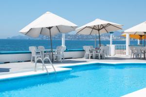 曼萨尼约Hotel Caracoles的水边带椅子和遮阳伞的游泳池