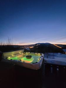 特吕西尔ReveEnka - cabin in Trysil with Jacuzzi for rent的雪中带灯光的按摩浴缸