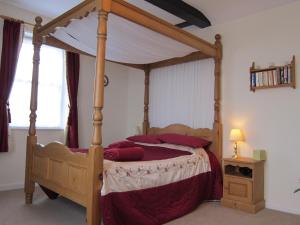 MartonBlack Swan Guest House的一间卧室配有一张带红色枕头的木制天蓬床