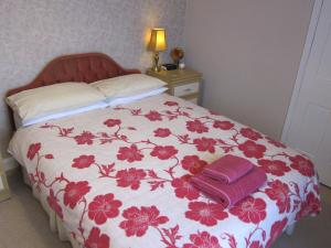 MartonBlack Swan Guest House的一张带红白色棉被的床,上面有两条毛巾