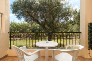 卡沃斯Oliveland Apartments的庭院里种着一棵树,上面摆放着白色的桌子和椅子