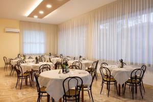 里米尼乔奥多酒店的一间设有桌椅和白色桌布的房间