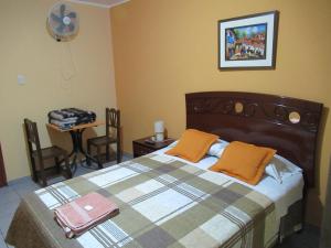 利马Kurmi Hostel Lima Airport的一间卧室配有一张床和一张带风扇的桌子。