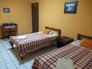 利马Kurmi Hostel Lima Airport的酒店客房设有两张床和一张桌子。