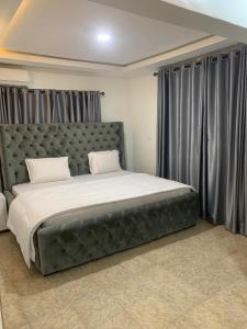 拉各斯Weena Hotel & Resort的卧室配有一张带灰色窗帘的大床