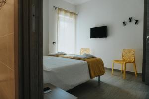 Leporano MarinaHarmony Guest House的一间卧室配有一张床、一台电视和两把椅子