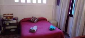 里奥塞瓦约斯Habitación en casa con pileta en Río Ceballos的小卧室配有粉红色的床和鞋