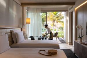 马斯喀特Jumeirah Muscat Bay Oman的站在酒店房间,带两张床的男人