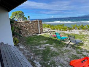 TemaeMoorea Lodge的一个带两把椅子和石墙的院子和大海