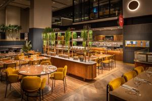 奥克兰voco Auckland City Centre, an IHG Hotel的一间带桌椅的餐厅和一间酒吧