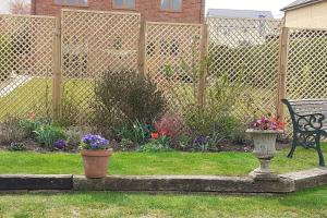 ElmswellThe Annexe, Cornfields的一个带长凳和鲜花的花园和一个围栏