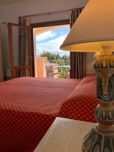 切尔沃港蒙蒂迪莫拉酒店的一间卧室配有一张红色的床,桌子上放着一盏灯