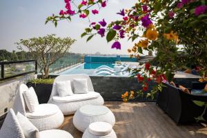 宁平Lalita Boutique Hotel & Spa Ninh Binh的阳台配有白色椅子,享有游泳池的景色