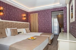 迪迪姆THE LEA HOTELS & SUITE的酒店客房带两张床和紫色瓷砖