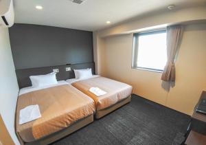北九州HOTEL LiVEMAX Kokura Ekimae的酒店客房设有两张床和窗户。