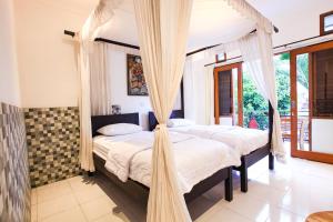 乌布巴厘岛巴提克斯卡尔民宿的卧室内的两张床,配有蚊帐