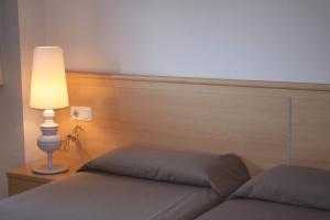 卡斯特尔德费尔斯马索尔公寓式酒店的一间卧室配有一张带灯和床头板的床