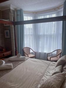 布莱克浦Riversvale Hotel的一间卧室配有一张大床、两把椅子和一扇窗户