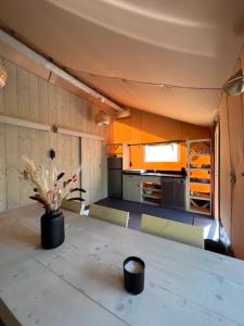瑞斯Luxe Safaritent Medley 5 persoons op Camping Rijsterbos的厨房配有一张桌子,上面放着花瓶