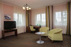 波杰布拉迪Hotel Zámeček的客厅配有电视、椅子和桌子