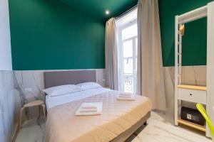 那不勒斯P.C. Boutique Medina H. Napoli Centro, by Clapa Group的一间卧室设有绿色的墙壁和一张带毛巾的床。