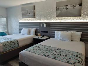巴拿马城海滩Casa Loma Panama City Beach - Beachfront的酒店客房,设有两张床和两张墙上的照片