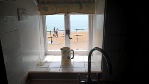 莱姆里吉斯Dolphin Cottage Lyme Regis的厨房里的一个窗户,前面有咖啡杯