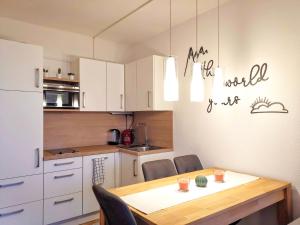 巴德哥依斯恩Jonas Deluxe Apartment Panoramablick的一间带木桌的厨房和一间带白色橱柜的厨房