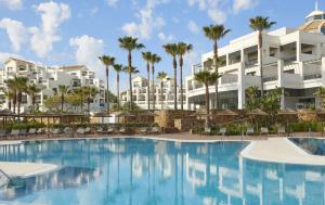 EsteponaEstepona Hotel & Spa Resort的一座楼前棕榈树游泳池