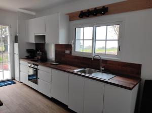 康卡勒Ty gwenn的厨房配有白色橱柜、水槽和2扇窗户。