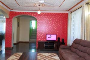 蒙巴萨SERENE 4 BEDROOMED HOME IDEAL FOR FAMILY HOLIDAY的一间客厅,在红色的墙上配有电视