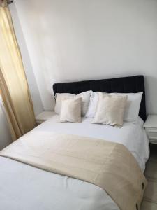 内罗毕Lovely 2 and 1 bedroom guest units Karen的白色的床、白色枕头和黑色床头板