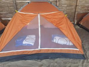 曼克拉Pepon Surf Camp的沙子上的一个橙色和蓝色的帐篷
