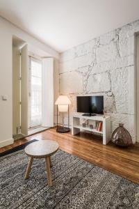 波尔图鲁亚特拉斯公寓的一间带电视和白色砖墙的客厅