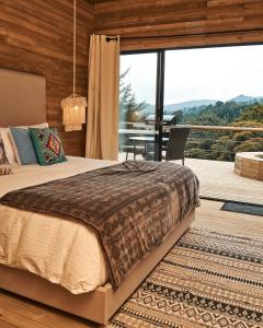 里奥内格罗Bleu Hills Glamping Llanogrande的一间卧室配有一张床,阳台配有桌子