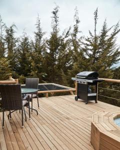 里奥内格罗Bleu Hills Glamping Llanogrande的木甲板上的烧烤架,配有桌椅