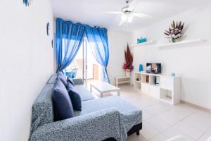 拉斯加莱塔斯Las Galletas House的客厅设有蓝色的沙发和窗户。