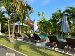 乌鲁瓦图宾津家庭简易别墅酒店的毗邻度假酒店的带椅子和遮阳伞的游泳池