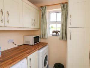 海上费萨德Grange Farmhouse的洗衣房配有洗衣机和烘干机以及窗户。