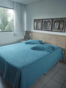 嘎林海斯港Flat Experience Marulhos Resort的一间卧室配有一张带蓝色床单的床和一扇窗户。