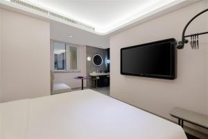 青岛青岛国际会展中心轻居酒店的卧室配有一张床和壁挂式平面电视。