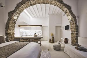 米克诺斯城Elaia Luxury Suites Mykonos的一间卧室设有拱门、一张床和一张书桌