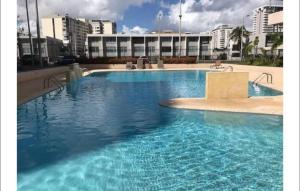 圣胡安Isla Verde Beach Modern apartment的一个大型蓝色游泳池,其建筑背景为: