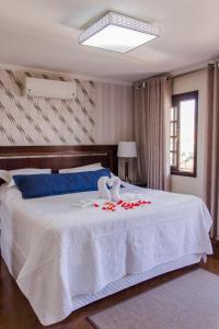 库里提巴Pousada da Paz的卧室配有带玫瑰花的白色床
