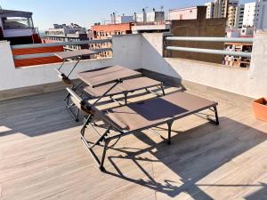 韦尔瓦Luxury Attics Avenida Italia PARKING INCLUIDO的建筑物屋顶上的两张野餐桌