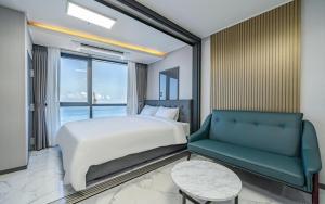 釜山Songjeong Blue Castle Hotel的一间卧室配有一张床、一张沙发和一个窗口