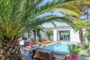 滨海拉库阿尔德Villa Lizelya的一座棕榈树游泳池和一座房子