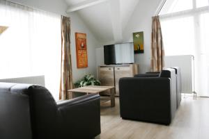 赫鲁斯贝克Hotel & Appartementen - De Zeven Heuvelen的客厅配有2把黑色椅子和电视