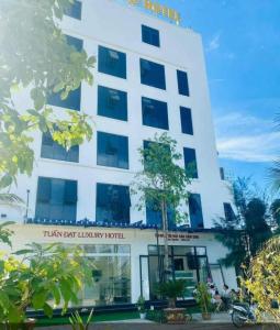 岑山Tuấn Đạt Luxury FLC Sầm Sơn的白色的建筑,上面标有读到泰坦最佳豪华酒店的标志
