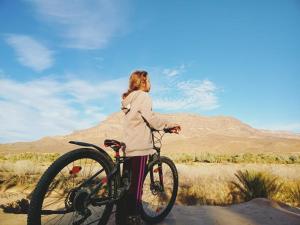 扎古拉Dar Hnini的站在沙漠自行车旁的女人